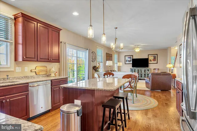 a kitchen with stainless steel appliances granite countertop a stove top oven a sink dishwasher a dining table and chairs with wooden floor