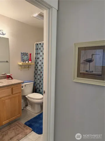 a bathroom with a granite countertop toilet a sink and a mirror