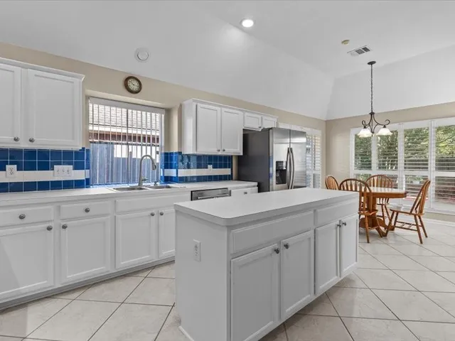 a kitchen with white cabinets stainless steel appliances and a refrigerator