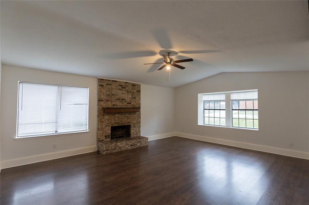 1031 East Peters Colony Road Carrollton, TX 75007 - Photo 4 of 21 a view of an empty room with wooden floor fireplace and a window