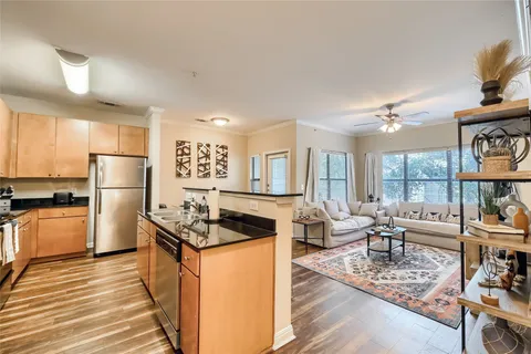 a kitchen with stainless steel appliances granite countertop a stove refrigerator and a dining table with wooden floor