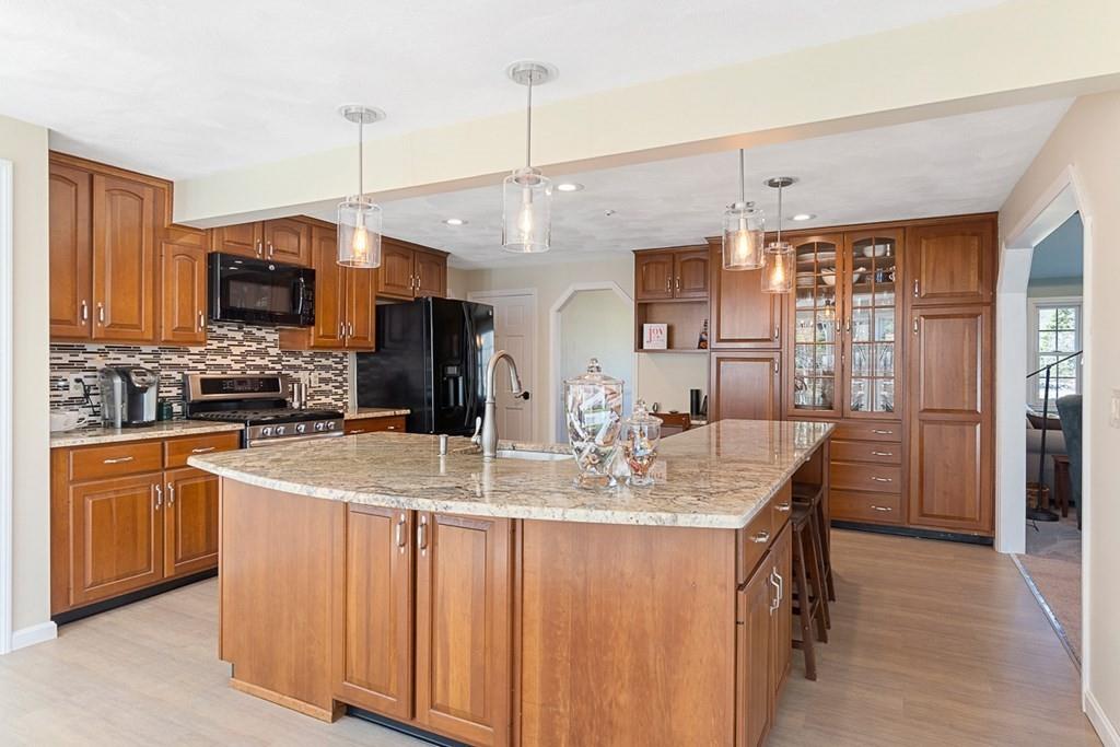 1 Fairview Drive Westford, MA 01886 - Photo 11 of 42 a kitchen with stainless steel appliances kitchen island granite countertop a stove a sink a refrigerator and a dining table with wooden floor