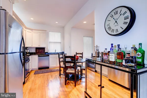 a kitchen with stainless steel appliances granite countertop a dining table chairs stove and white cabinets