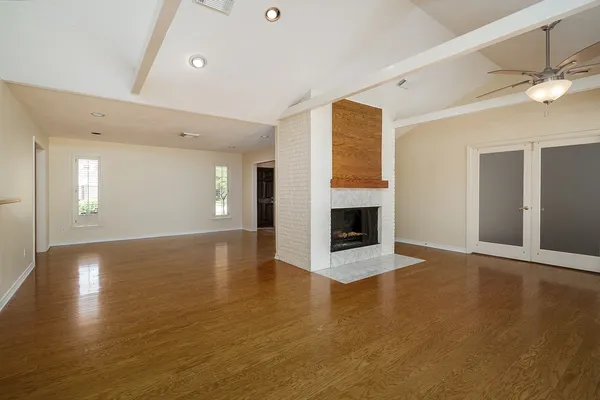 a view of an empty room with wooden floor and a fireplace