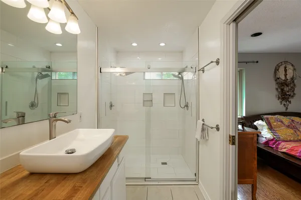 a bathroom with a tub shower sink and mirror
