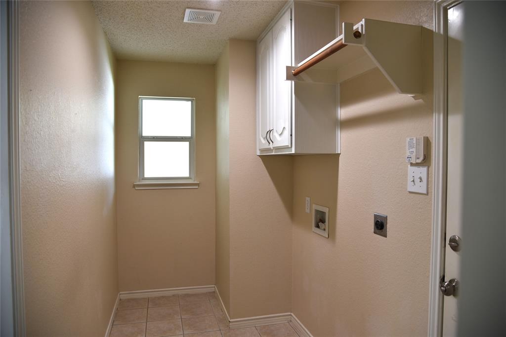 1526 Pebblestone Court Allen, TX 75002 - Photo 25 of 28 Utility room featuring tile flooring, a window, upper cabinetry, and a clothes-hanging rod
