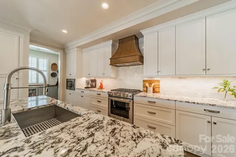a kitchen with granite countertop a stove a sink and a refrigerator