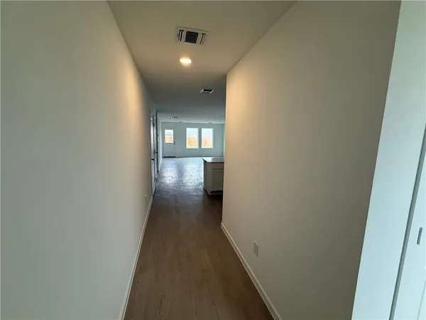 a view of a hallway with wooden floor and a bathroom