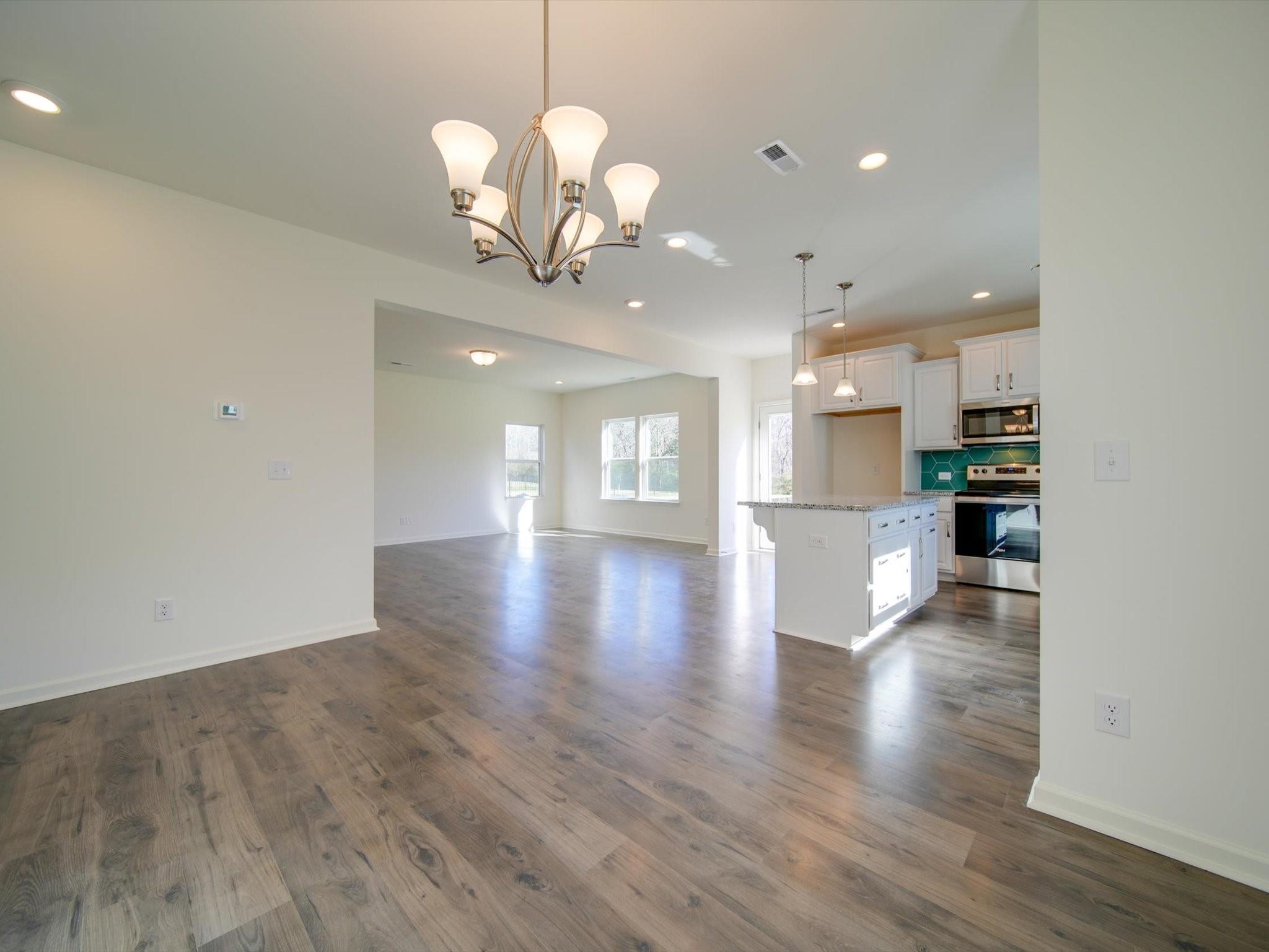 1172 Scotch Meadows Loop Monroe, NC 28110 - Photo 11 of 44 a view of a hallway with wooden floor and a kitchen