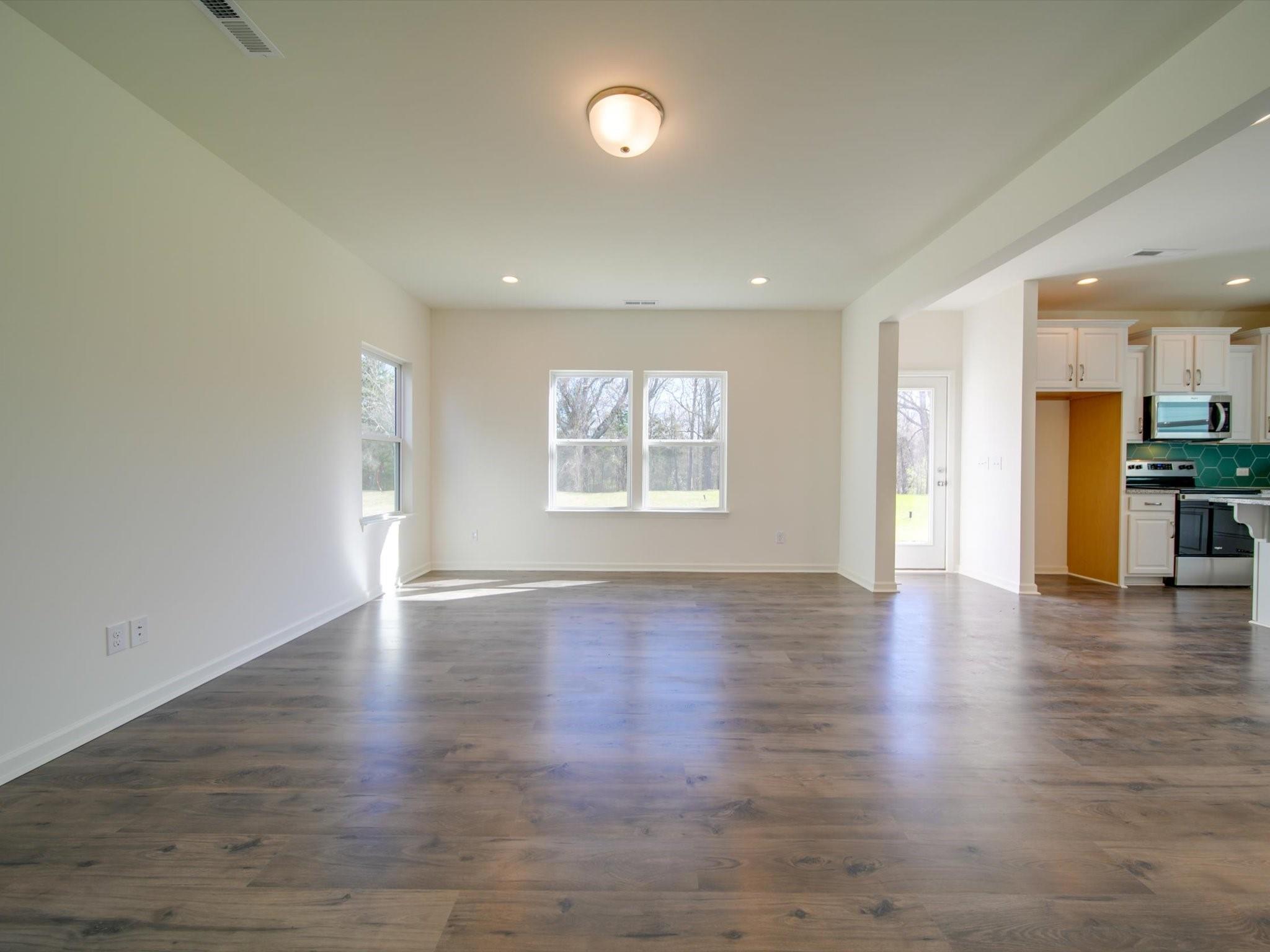 1172 Scotch Meadows Loop Monroe, NC 28110 - Photo 17 of 44 an empty room with wooden floor chandelier and windows