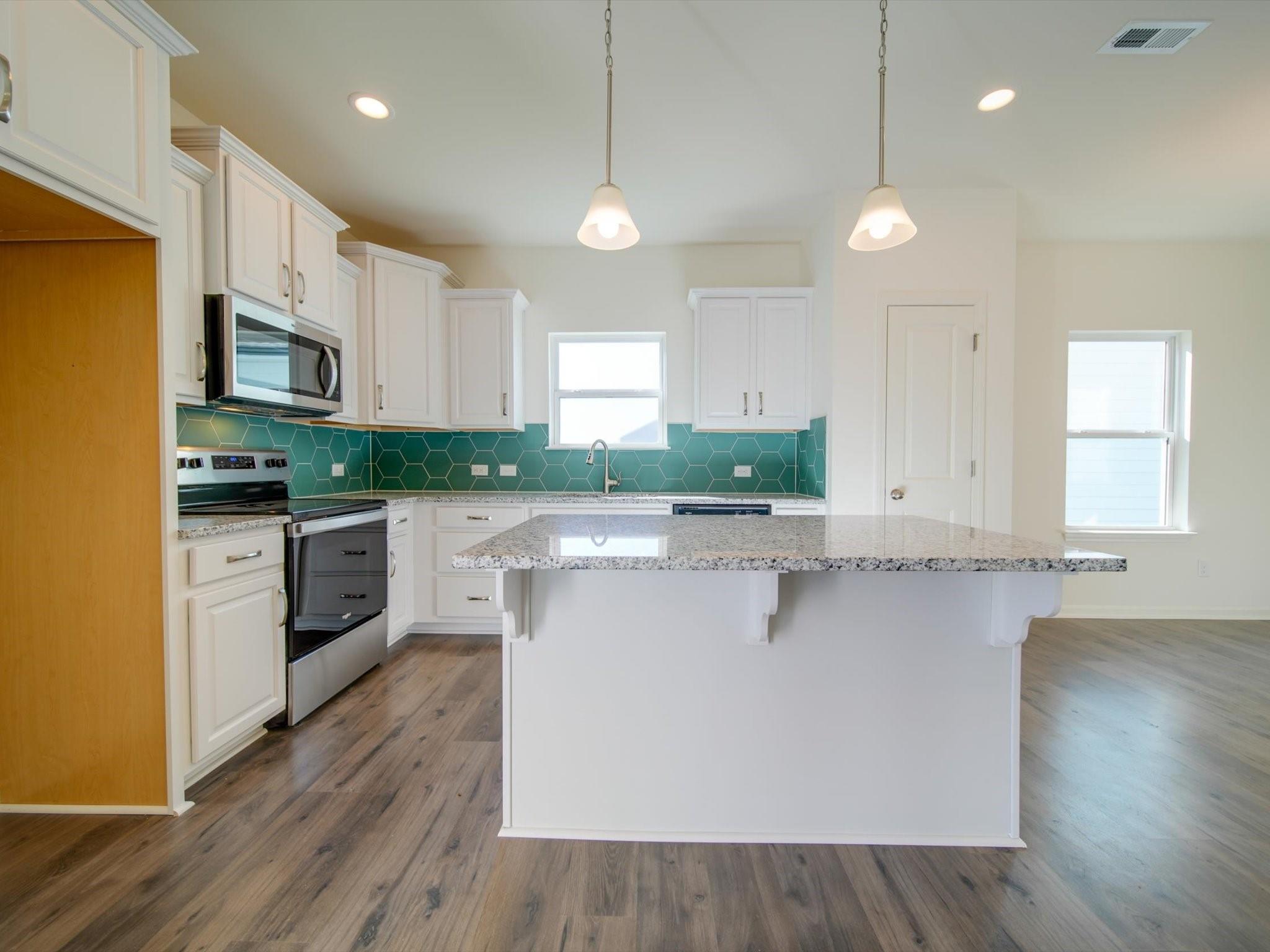 1172 Scotch Meadows Loop Monroe, NC 28110 - Photo 8 of 44 a kitchen with stainless steel appliances a sink a stove a refrigerator cabinets and a wooden floor