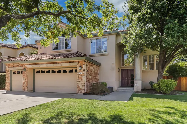 a front view of a house with a garden and trees