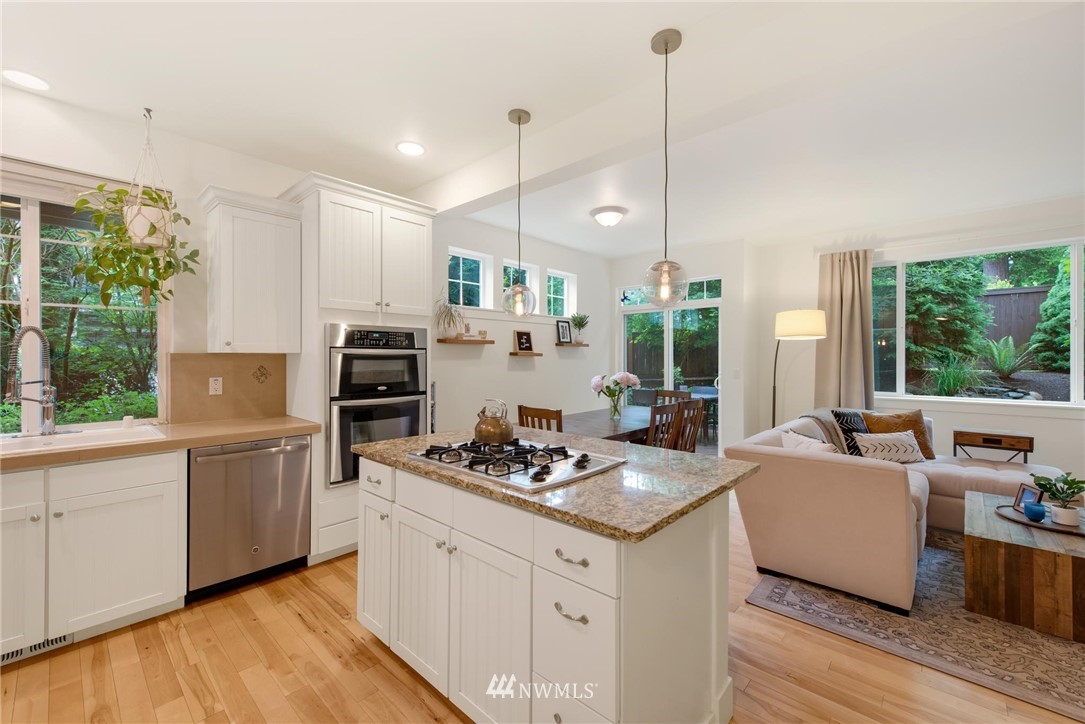 16203 41st Drive Southeast Bothell, WA 98012 - Photo 5 of 20 a kitchen with stainless steel appliances kitchen island granite countertop a stove a sink dishwasher a refrigerator and a dining table with wooden floor