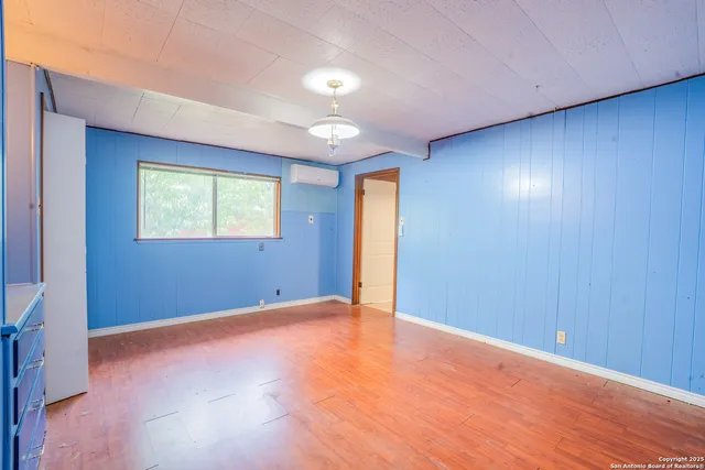 a view of an empty room with window and wooden floor