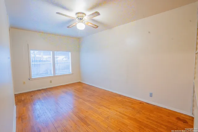 an empty room with windows and fan