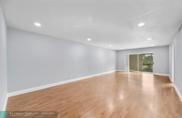 an empty room with wooden floor and window