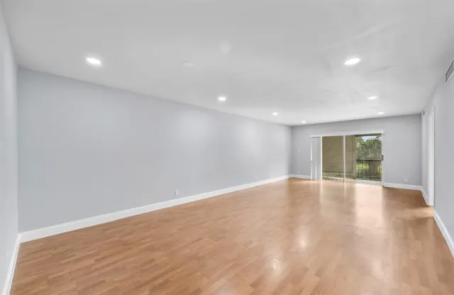 an empty room with wooden floor and window