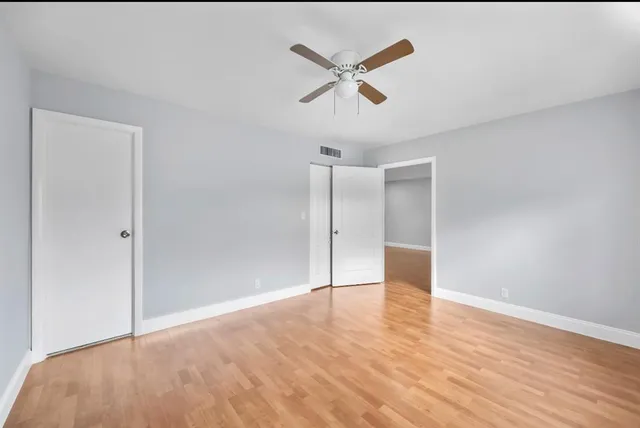 a view of empty room with wooden floor and ceiling fan