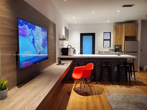 a living room with stainless steel appliances granite countertop furniture rug and wooden floor