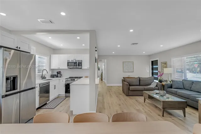 a living room with stainless steel appliances furniture and a kitchen view