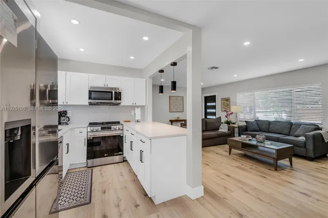 a living room with stainless steel appliances furniture and a kitchen view
