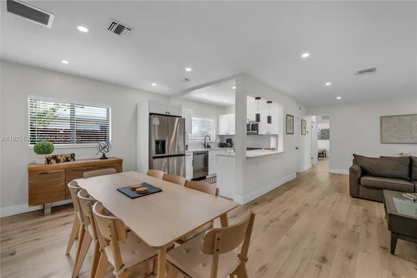 a kitchen with stainless steel appliances kitchen island granite countertop a dining table chairs and refrigerator