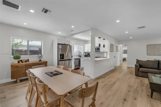 a kitchen with stainless steel appliances kitchen island granite countertop a dining table chairs and refrigerator
