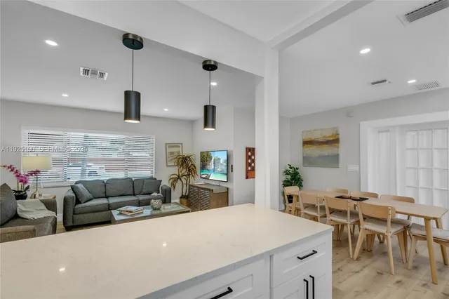 a living room with furniture kitchen view and a large window