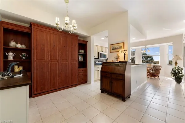 a living room with stainless steel appliances kitchen island granite countertop a refrigerator and a wooden cabinets