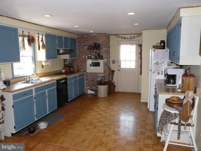 a kitchen with stainless steel appliances granite countertop a stove top oven a sink dishwasher a refrigerator and cabinets with wooden floor