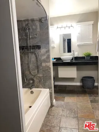 a bathroom with a tub a sink and mirror