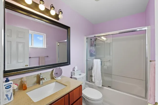 a bathroom with a sink vanity granite toilet and shower