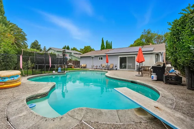 a view of a house with swimming pool lawn chairs and a yard