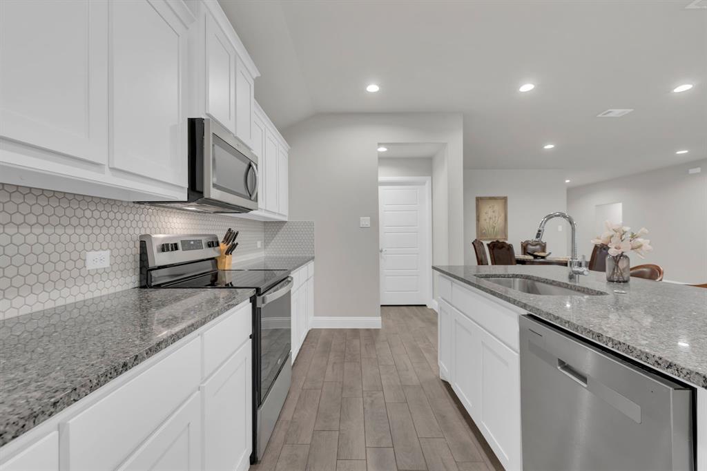 728 Golden Gate Pk Road Alvarado, TX 76009 - Photo 7 of 23 Kitchen with stainless steel appliances, light stone counters, white cabinets, decorative backsplash, and light wood-style floors