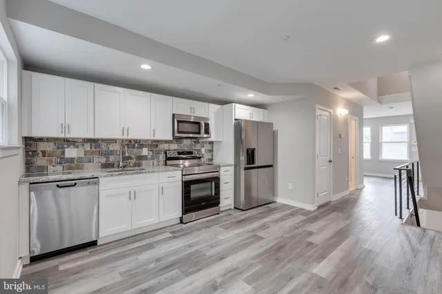 a kitchen with granite countertop a refrigerator and a stove top oven