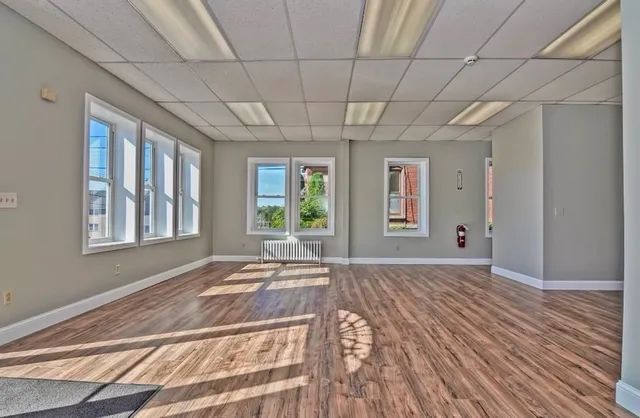 a view of an empty room with a window and wooden floor