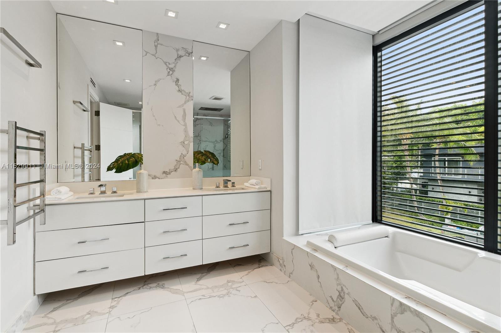 4060 Woodridge Road Miami, FL 33133 - Photo 16 of 49 a bathroom with a double vanity sink a large mirror a bathtub and next to a window