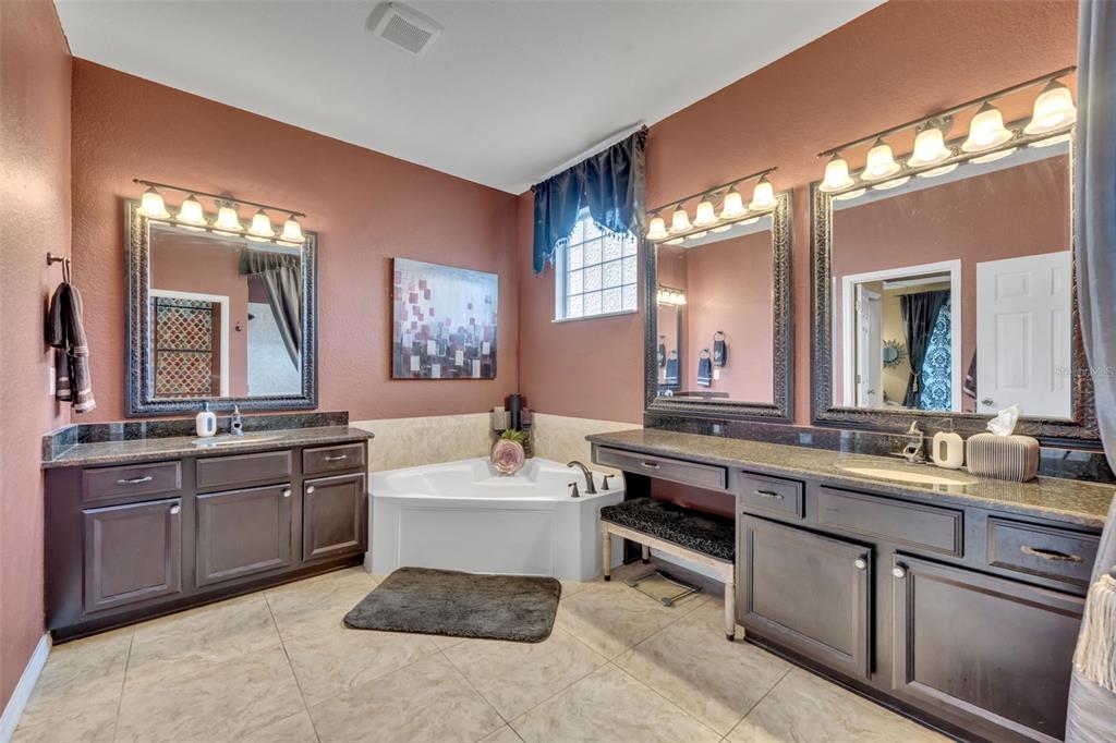 4946 Northeast 124th Road Oxford, FL 34484 - Photo 30 of 69 a large bathroom with a double vanity sink a large mirror and a bathtub