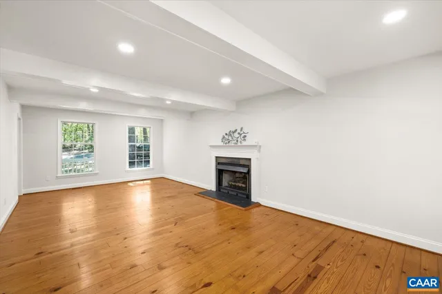 an empty room with windows and fireplace