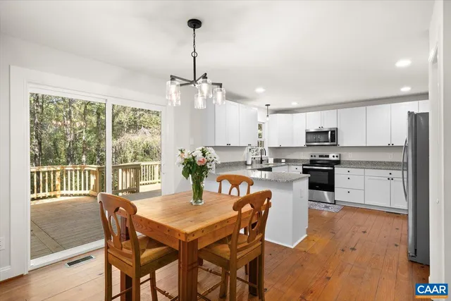 a view of a dining room and livingroom with furniture wooden floor a chandelier