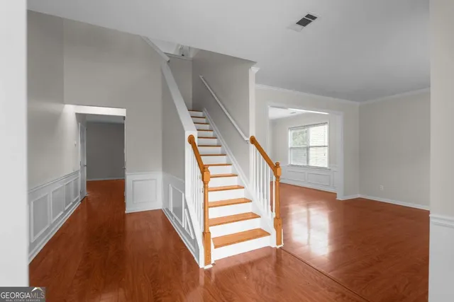 a view of a hallway with wooden floor and stairs