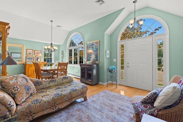 a living room with furniture a chandelier and a wooden floor
