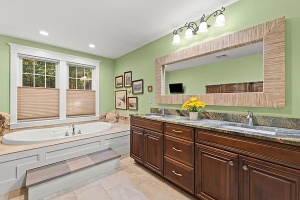a spacious bathroom with a double vanity sink large mirror and a bathtub