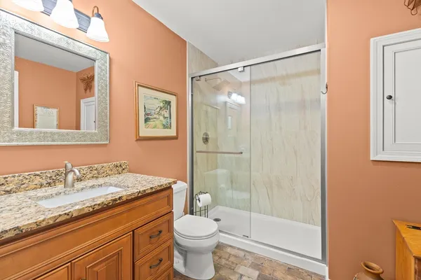 a bathroom with a granite countertop sink a toilet and shower