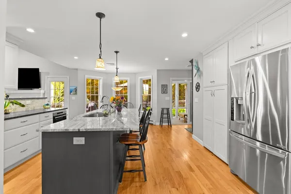 a large kitchen with stainless steel appliances kitchen island granite countertop a refrigerator and a stove top oven