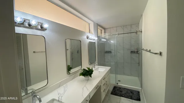 a bathroom with a double vanity sink a toilet a mirror and shower