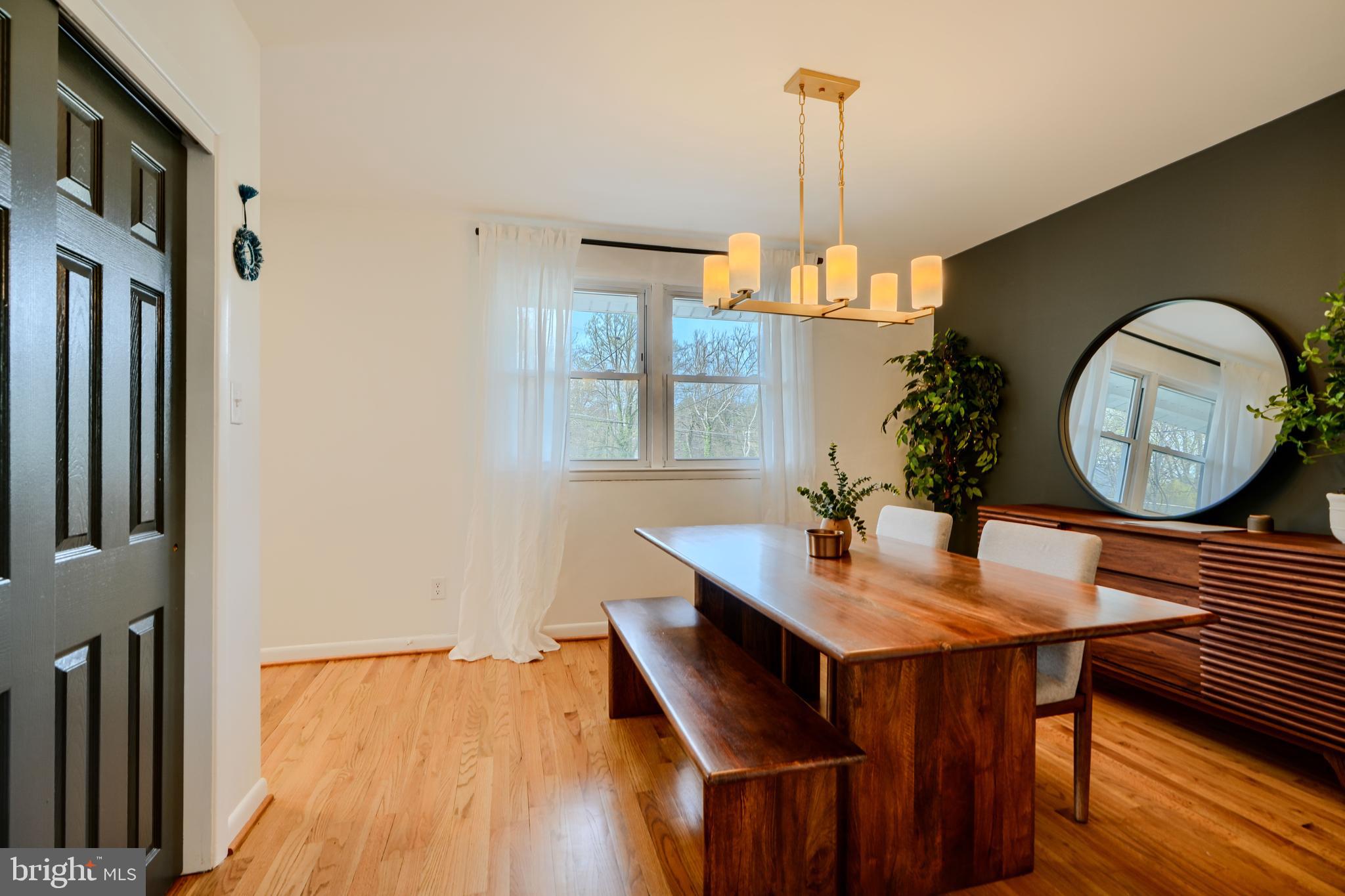 1103 Litchfield Road, Unit H Baltimore, MD 21239 - Photo 23 of 74 a dining room with wooden floor a chandelier a wooden table and chairs