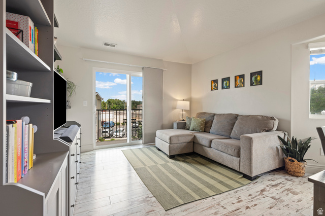 8248 South Resaca Drive, Unit J10 Sandy, UT 84070 - Photo 10 of 40 Living area featuring light wood-finish flooring and a sliding glass door to a balcony