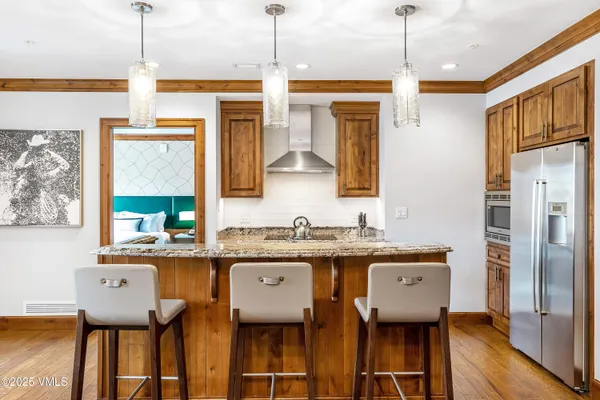 a kitchen with stainless steel appliances granite countertop a sink a refrigerator and a wooden floor