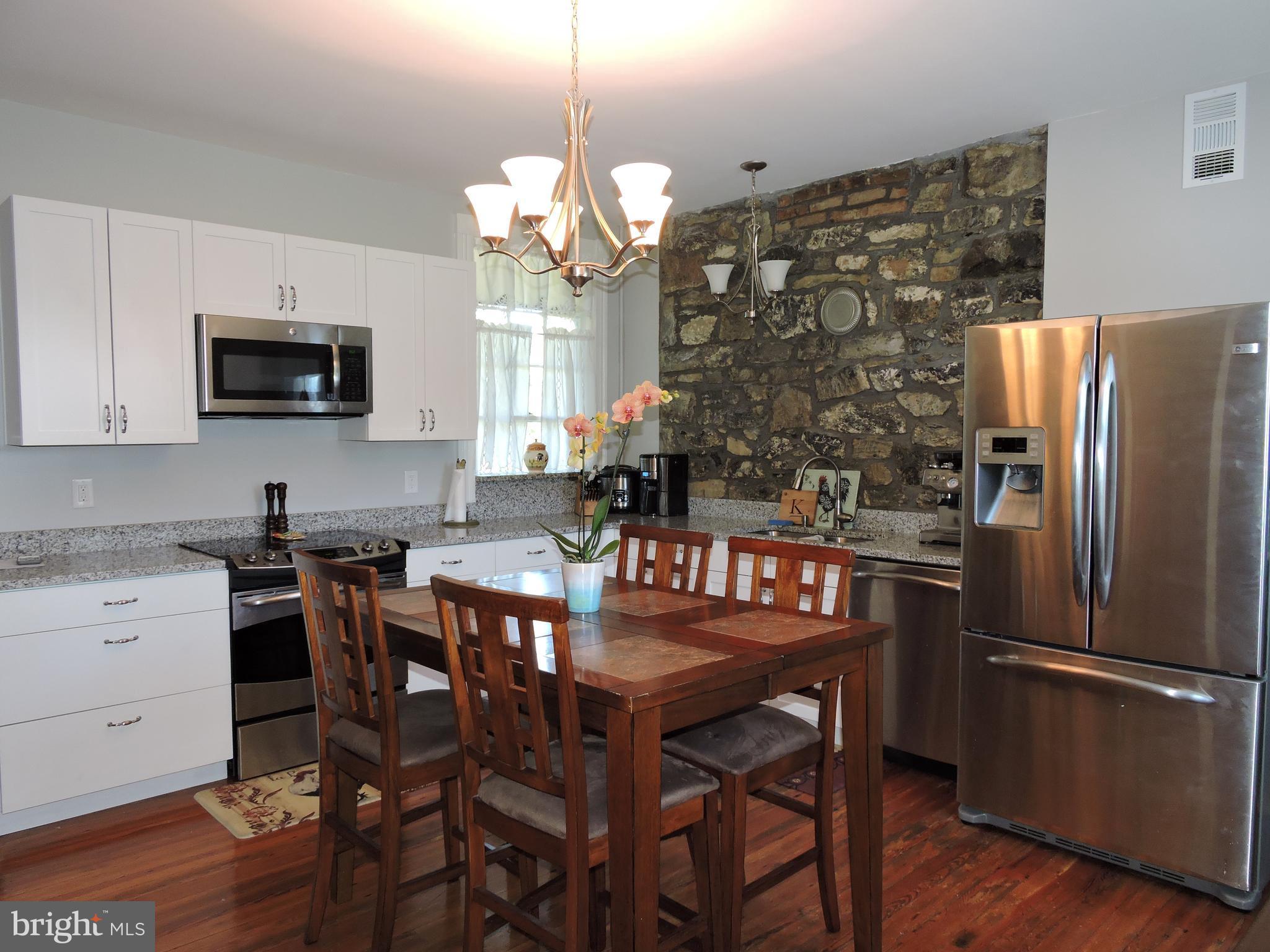 3047 Kabletown Road Charles Town, WV 25414 - Photo 12 of 30 a kitchen with stainless steel appliances granite countertop a refrigerator a stove a microwave oven a sink a dining table and chairs with wooden floor